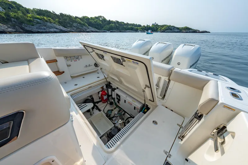 Slide: The Image of 2019 Boston Whaler 350 EX REALM boat with open storage compartment, docked near scenic shoreline. - 28