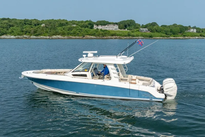 Slide: The Image of 2019 Boston Whaler 350 EX REALM cruising on calm waters near a lush shoreline. - 41
