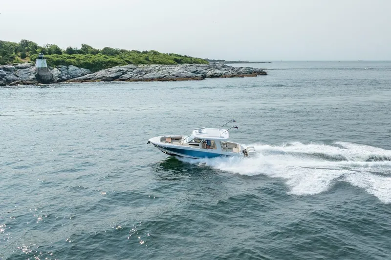 Slide: The Image of 2019 Boston Whaler 350 EX REALM cruising near rocky shoreline and lighthouse. - 44