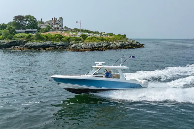 Slide: The Image of 2019 Boston Whaler 350 EX REALM cruising near scenic coastal estate. - 47