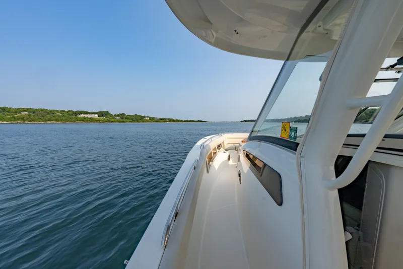 Slide: The Image of 2019 Boston Whaler 350 EX REALM cruising on calm waters, scenic shoreline view. - 7
