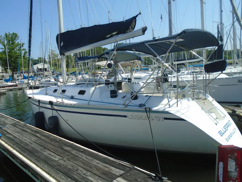 Slide: The Image of 1987 Hunter Legend 37 sailboat docked at a marina, featuring sleek design and spacious deck. - 0