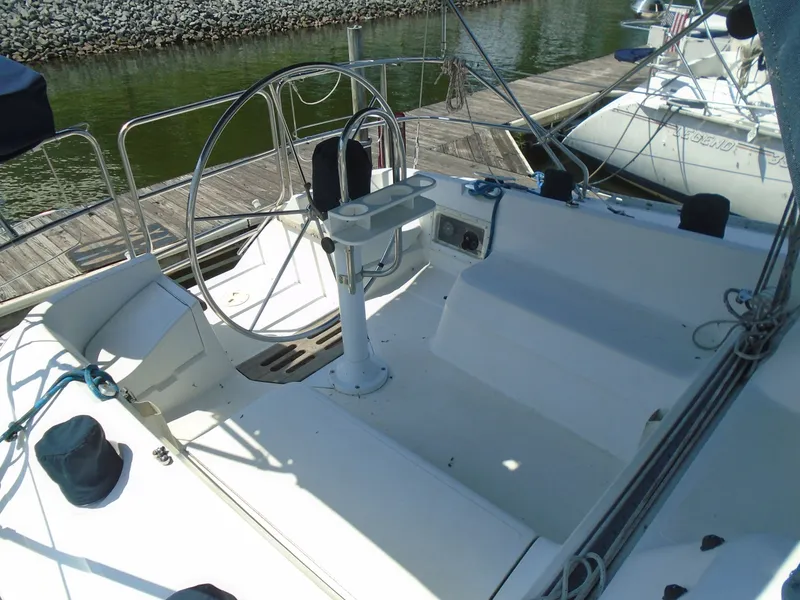 Slide: The Image of 1987 Hunter Legend 37 sailboat cockpit with steering wheel, docked by the water. - 1