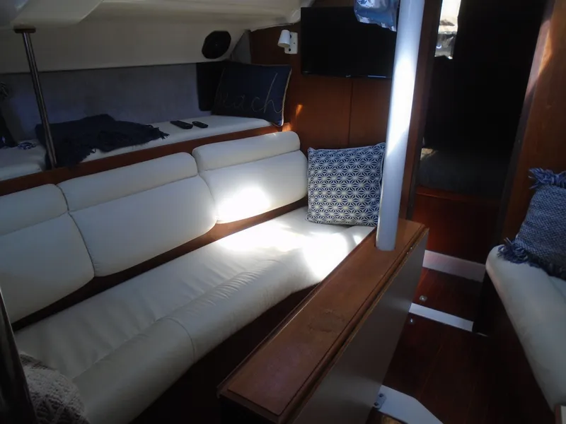 Slide: The Image of Interior of 1987 Hunter Legend 37 sailboat with white seating and decorative pillows. - 4