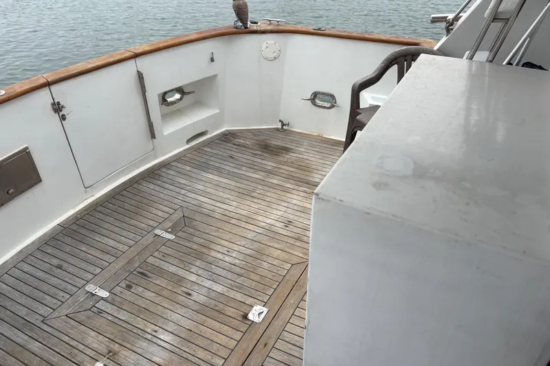 Slide: The Image of 1990 Angel Pilothouse boat deck with wooden flooring and white railings. - 15