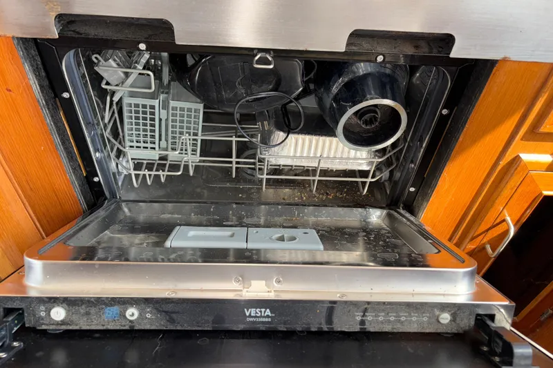 Slide: The Image of Open Vesta dishwasher with dishes inside, wooden cabinetry, Angel Pilothouse 1990 model. - 21