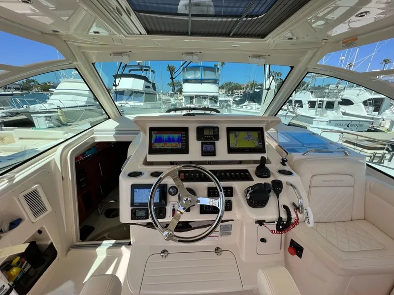 Slide: The Image of 2019 Grady-White Express 370 helm with advanced navigation systems, docked in a marina. - 2