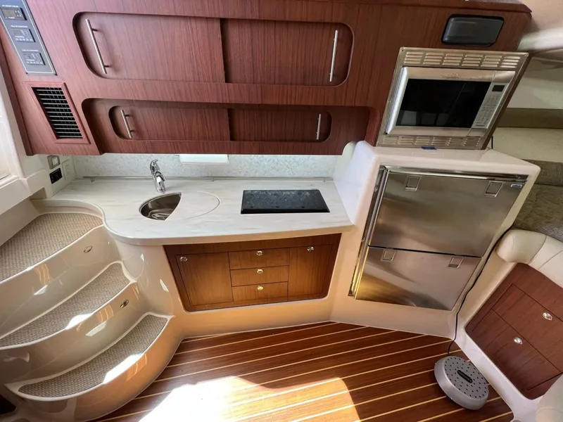 Slide: The Image of 2019 Grady-White Express 370 interior with kitchenette, wood cabinetry, and stainless steel appliances. - 7