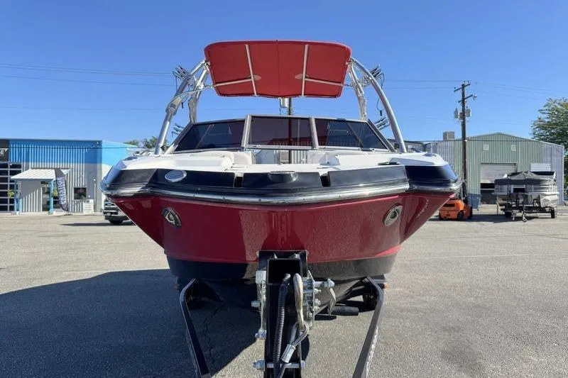 Slide: The Image of 2008 Chaparral 224 Extreme boat with red hull and canopy, parked on a trailer. - 2