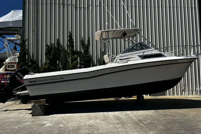 The Image of 1992 Grady-White Explorer 244 boat on display outside a metal building. - 0