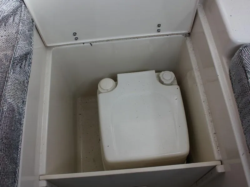 Slide: The Image of 1992 Grady-White Explorer 244 storage compartment with a white container inside. - 19