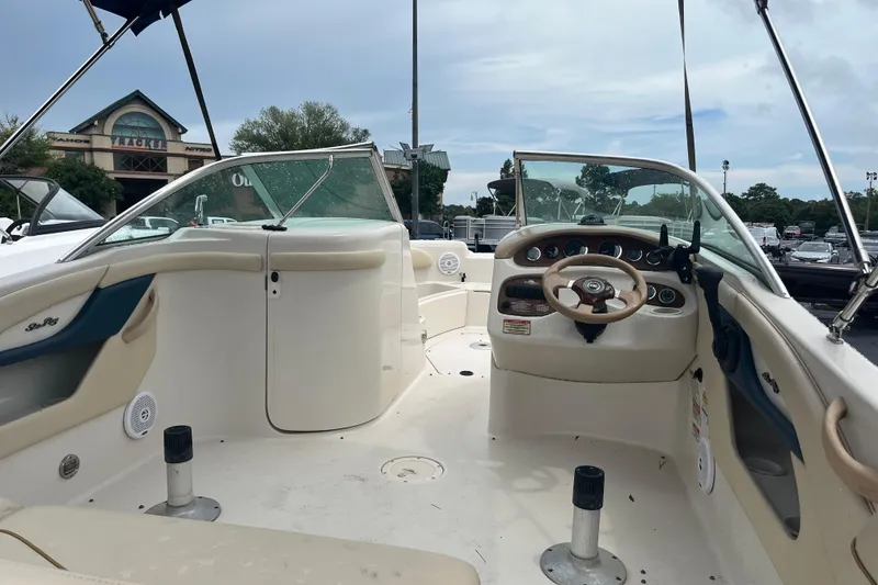 Slide: The Image of 2001 Sea Ray 210 Sundeck boat interior with steering wheel and seating, parked outdoors. - 3