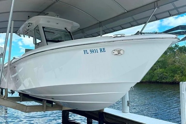 Slide: The Image of 2015 Everglades 295 Center Console boat docked under a canopy, side view. - 11