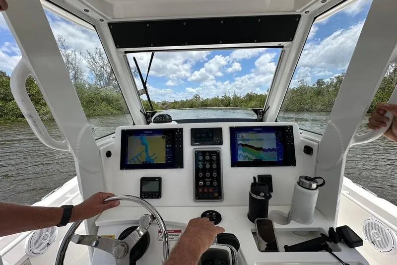 Slide: The Image of 2015 Everglades 295 Center Console boat dashboard with navigation screens on a scenic waterway. - 17