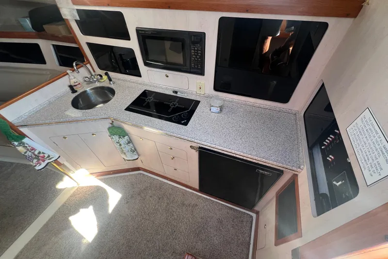 Slide: The Image of 1989 Luhrs 35 Alura boat kitchen with sink, stove, microwave, and compact fridge. - 12