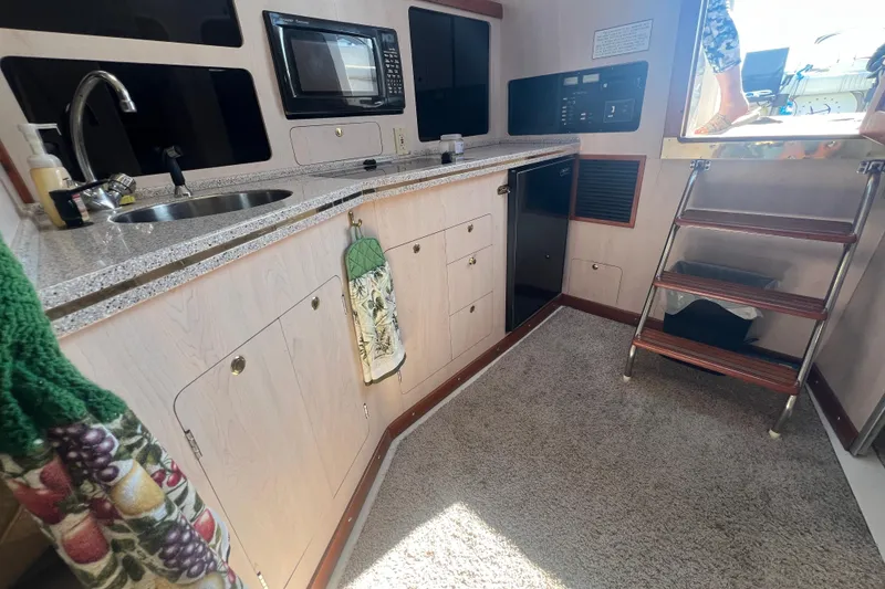 Slide: The Image of 1989 Luhrs 35 Alura boat interior with kitchenette, sink, microwave, and stairs. - 15