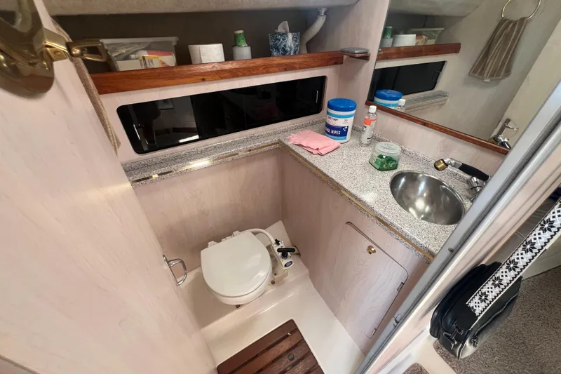 Slide: The Image of 1989 Luhrs 35 Alura boat bathroom with sink, toilet, and storage shelves. - 16
