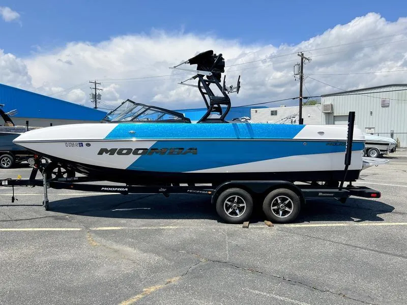 The Image of 2018 Moomba Mojo™ boat on trailer, blue and white design, parked outdoors. - 0