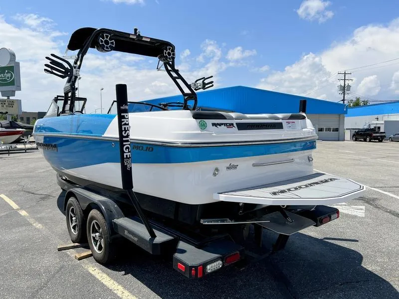 Slide: The Image of 2018 Moomba Mojo™ boat on trailer, blue and white, parked outdoors under a clear sky. - 11