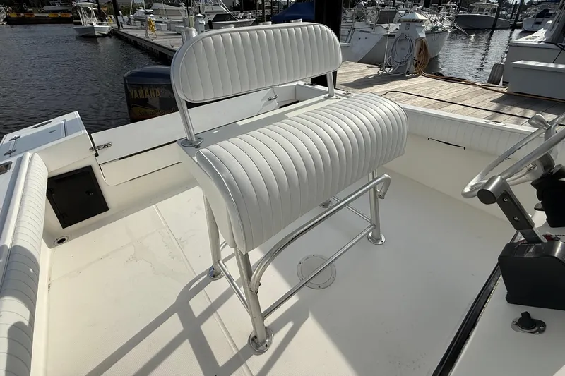 Slide: The Image of 2000 Regulator 23 Classic boat interior with white seating and steering wheel at dock. - 10