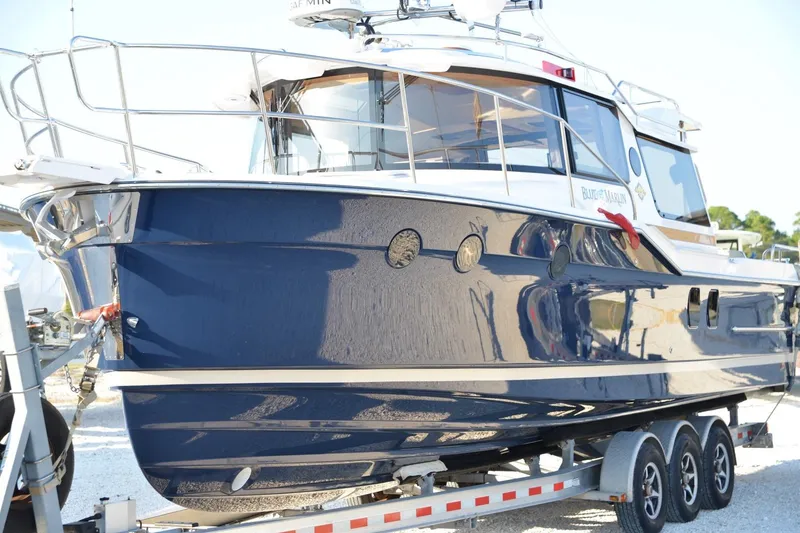 Slide: The Image of 2026 Ranger Tugs R-29 S boat on trailer, sleek blue exterior, docked outdoors. - 2