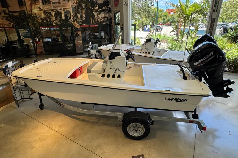 Slide: The Image of 2024 Mako 13 Pro Skiff CC boat displayed indoors with Mercury engine. - 4