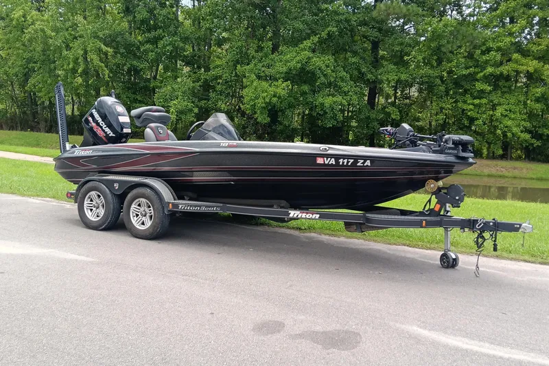 Slide: The Image of 2018 Triton 18 TrX boat on trailer, parked by a grassy area. - 2