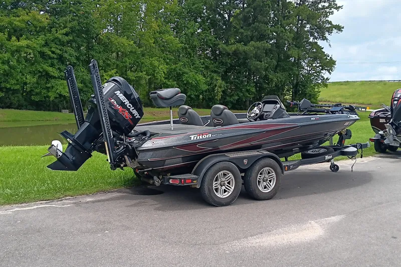 Slide: The Image of 2018 Triton 18 TrX bass boat on trailer, parked near a grassy area. - 3