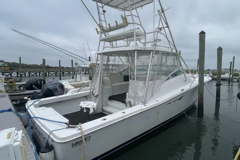 Slide: The Image of 1997 Luhrs 36 SX boat docked at marina, featuring fishing equipment and dual outboard motors. - 1