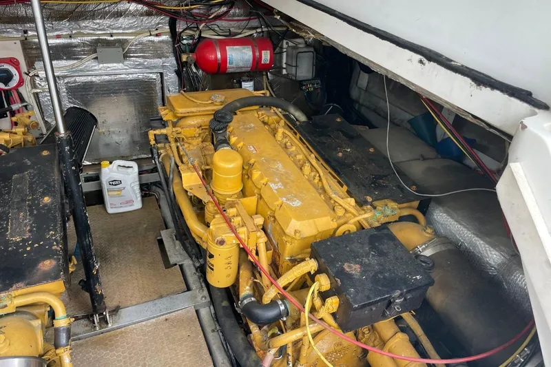 Slide: The Image of Engine room of a 1997 Luhrs 36 SX boat, featuring a yellow engine and fire extinguisher. - 39