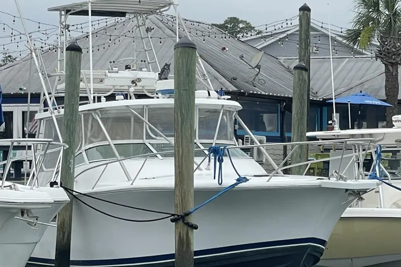 Slide: The Image of 1997 Luhrs 36 SX boat docked at a marina with surrounding vessels. - 5
