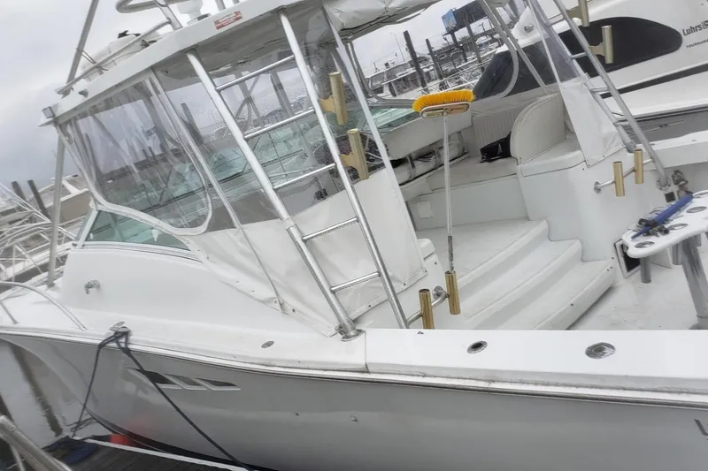 Slide: The Image of 1997 Luhrs 36 SX boat docked, featuring spacious deck and seating area. - 7