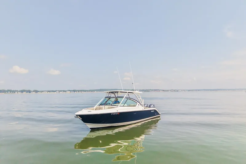 Slide: The Image of 2023 Pursuit DC 266 Dual Console boat on calm water under clear sky. - 1