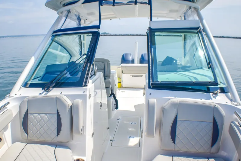 Slide: The Image of 2023 Pursuit DC 266 Dual Console boat interior with seating and windshield on calm water. - 10