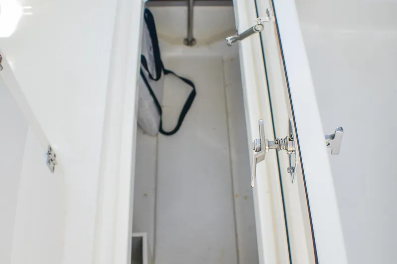 Slide: The Image of Storage compartment of 2023 Pursuit DC 266 Dual Console boat, featuring secure latches. - 16
