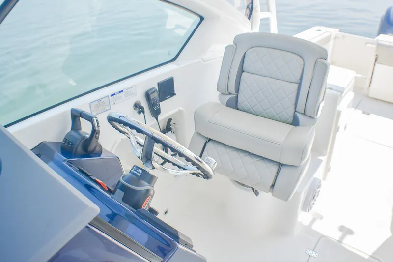 Slide: The Image of 2023 Pursuit DC 266 Dual Console boat interior with steering wheel and cushioned seat. - 17