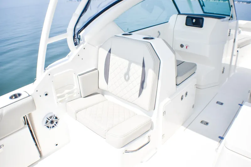 Slide: The Image of 2023 Pursuit DC 266 Dual Console boat interior with white seating and cup holders. - 22