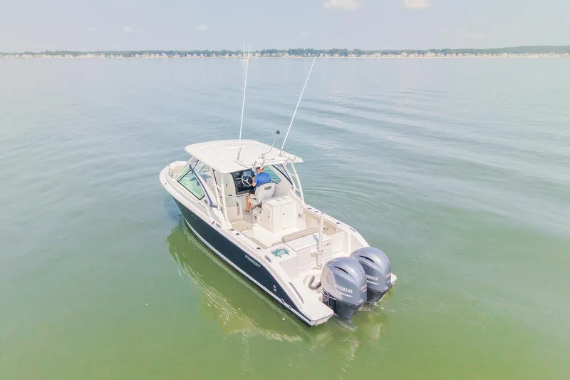 Slide: The Image of 2023 Pursuit DC 266 Dual Console boat on calm water, featuring twin Yamaha engines. - 3