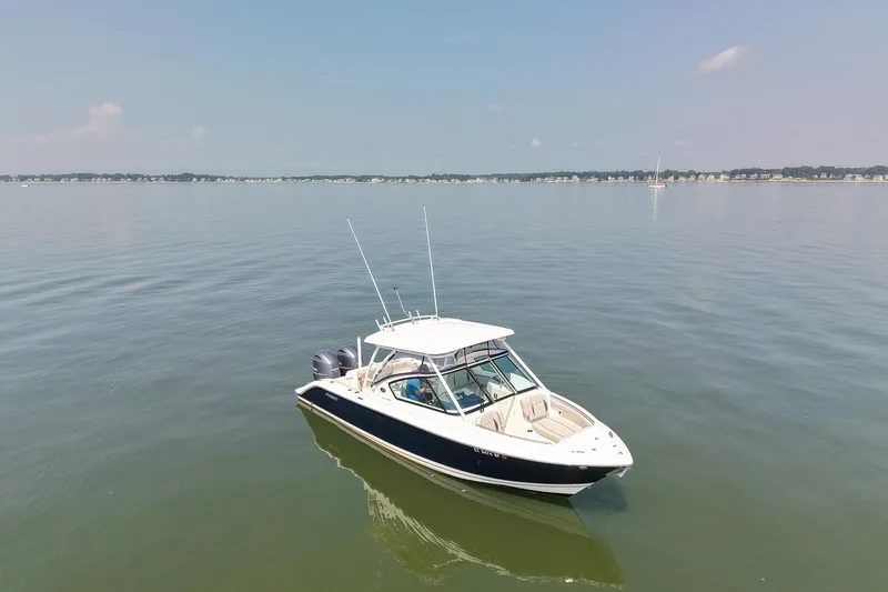 Slide: The Image of 2023 Pursuit DC 266 Dual Console boat on calm water under clear sky. - 7