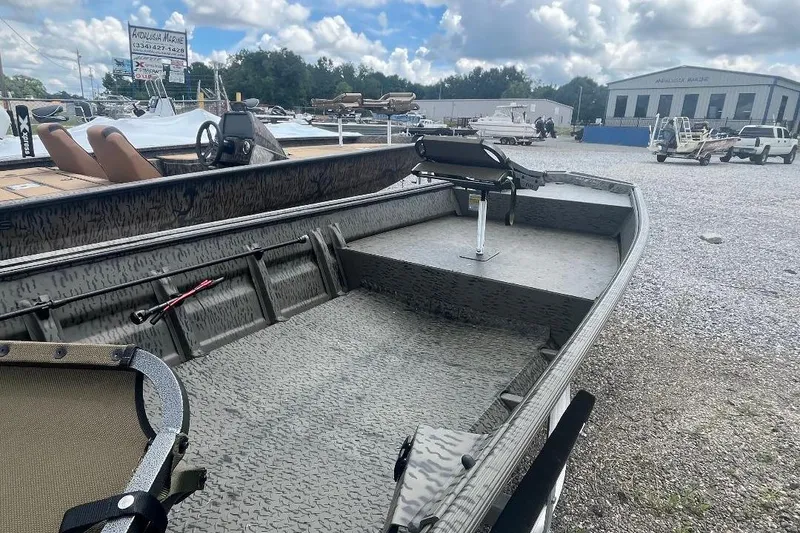 Slide: The Image of 2026 War Eagle 648LDV boat with camo interior, parked outdoors at a marine dealership. - 6