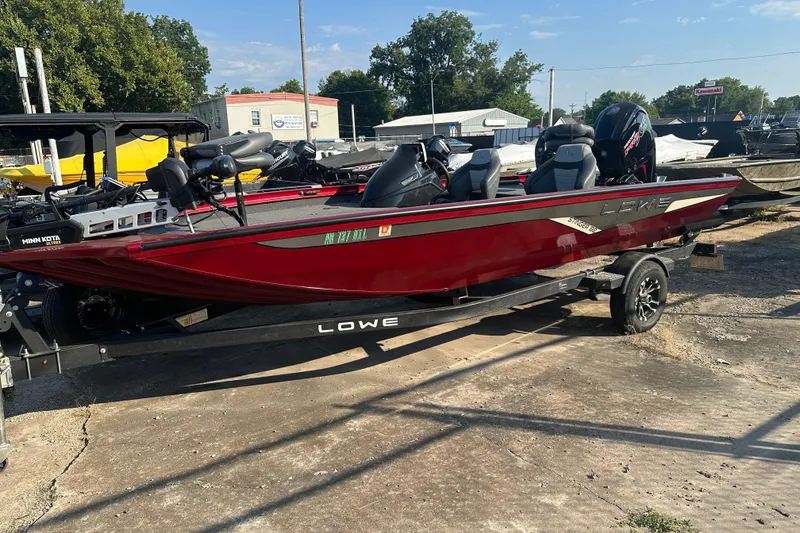 Slide: The Image of 2022 Lowe Stinger 188 boat in vibrant red on a trailer, parked outdoors. - 0