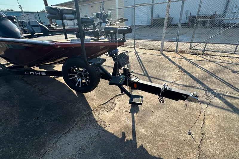 Slide: The Image of 2022 Lowe Stinger 188 boat on trailer, parked on concrete near a chain-link fence. - 8