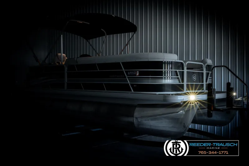 Slide: The Image of 2023 Godfrey SW2286C pontoon boat in a dimly lit showroom with headlights on. - 4