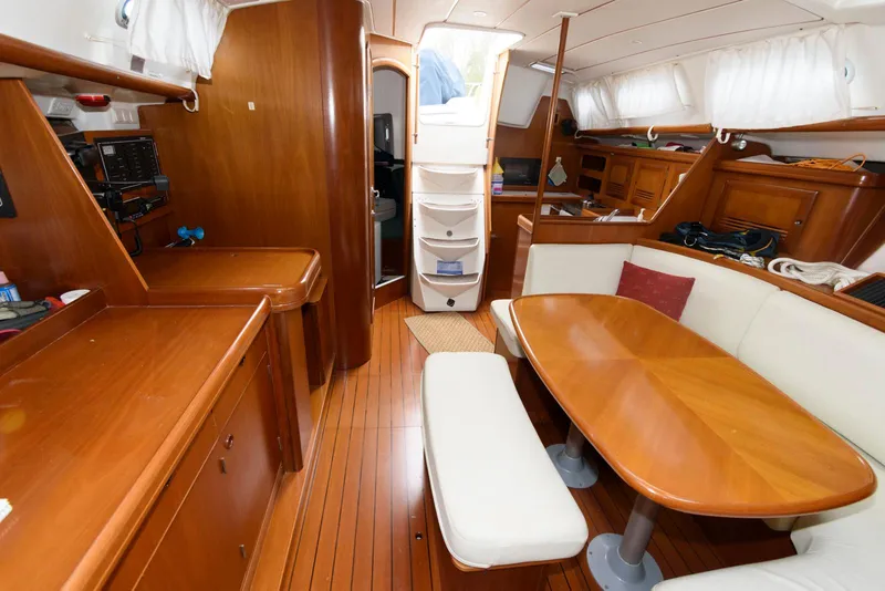 Slide: The Image of Interior of 2002 Beneteau 393 sailboat with wooden furnishings and dining area. - 12