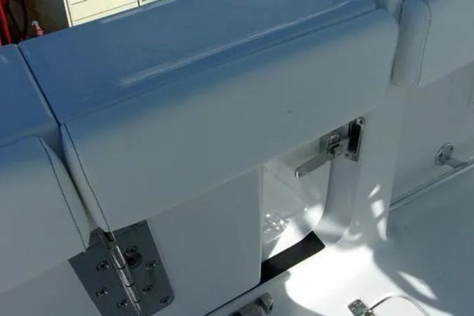 Slide: The Image of 2025 Sportsman Heritage 261 boat interior with white cushioned seating and metal hinges. - 14