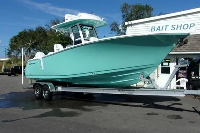 Slide: The Image of 2025 Sportsman Heritage 261 boat on trailer near bait shop, clear sky. - 3