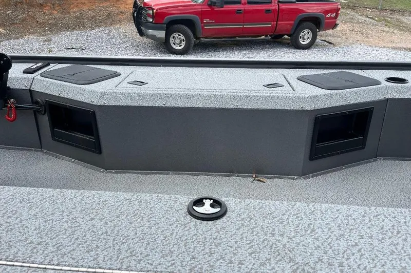 Slide: The Image of 2026 War Eagle 754VS Stick Steer boat interior with storage compartments, parked red truck in background. - 9