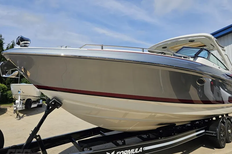 Slide: The Image of 2020 Formula 330 Crossover Bowrider on trailer, sleek design, parked outdoors. - 14