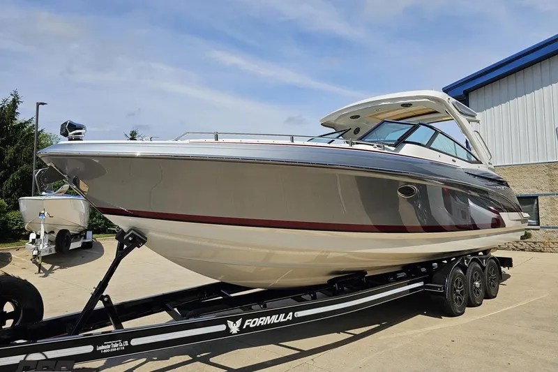 Slide: The Image of 2020 Formula 330 Crossover Bowrider on trailer, parked outdoors under clear sky. - 15