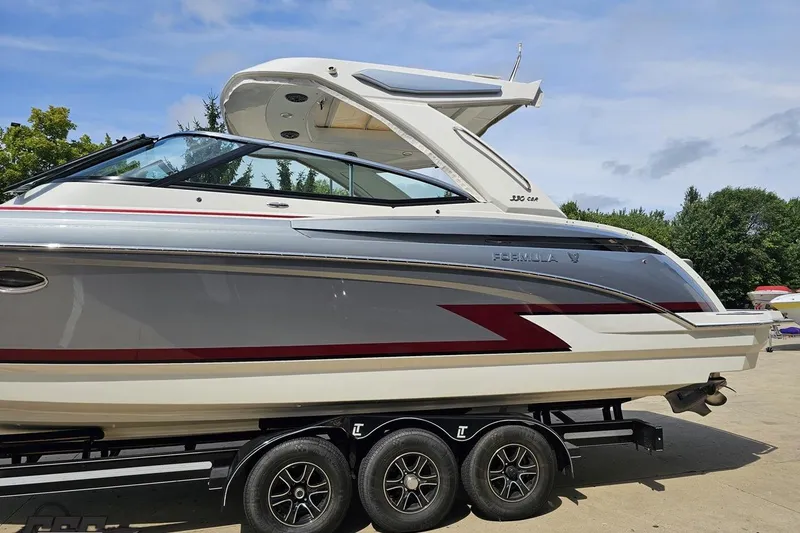 Slide: The Image of 2020 Formula 330 Crossover Bowrider boat on trailer, sleek design, parked outdoors. - 20